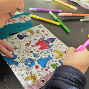 Enfant en train de colorier un coloriage en tissu sur le thème des princesses. Une partie du coloriage est déjà fait.